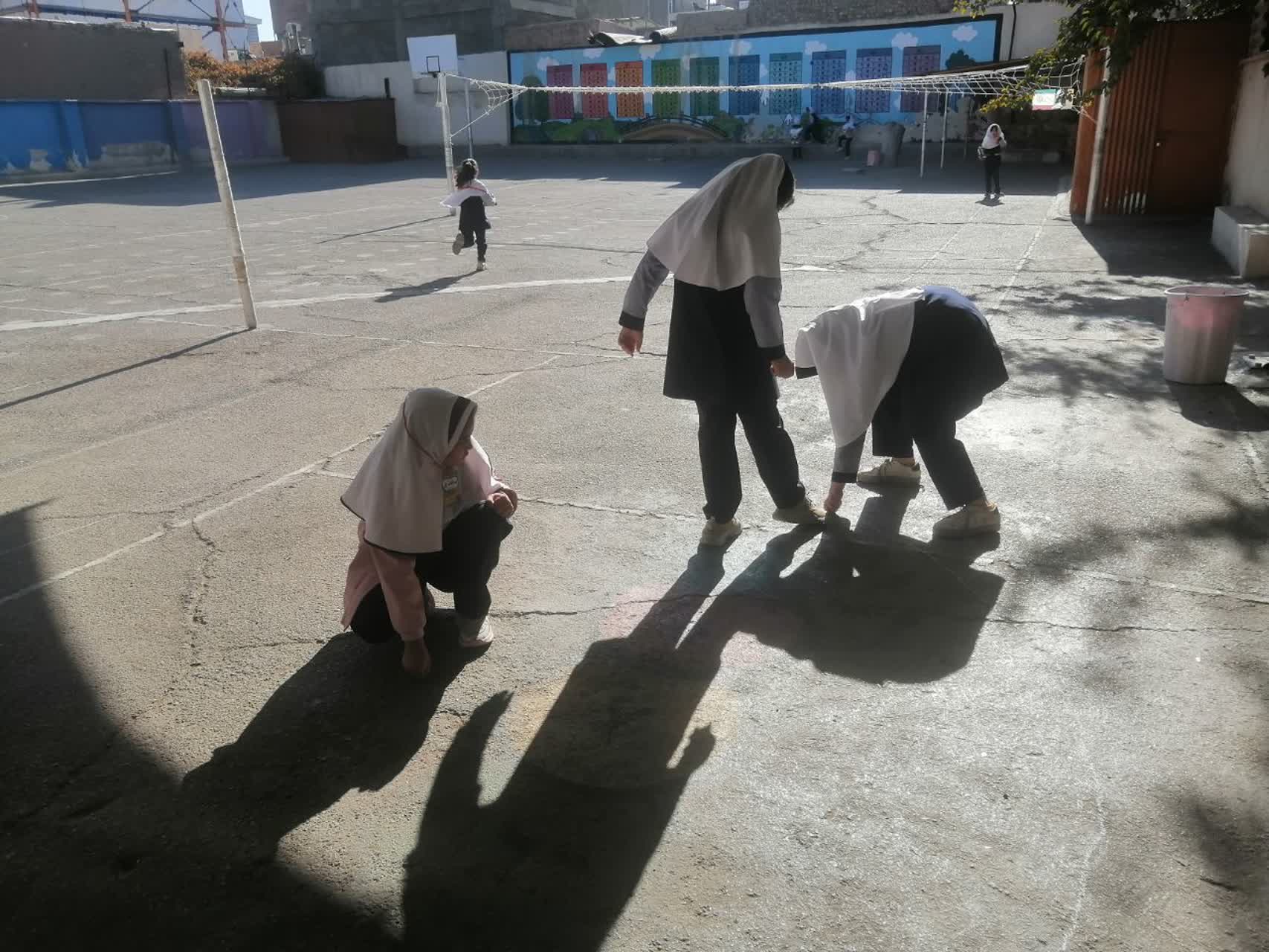 کشیدن دایره روی حیاط توسط دختران ، جهت آموزش کار با پرگار